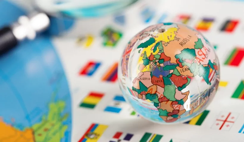 Small globe placed on a surface with various country flags, showing a close-up of Africa and surrounding regions.