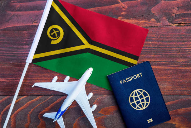 A passport, a small model airplane, and the flag of Vanuatu displayed on a white surface.